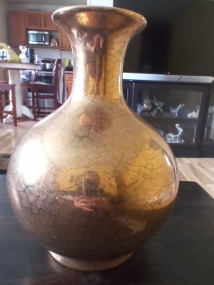 A gold colored ceramic vase.