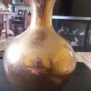 A gold colored ceramic vase.