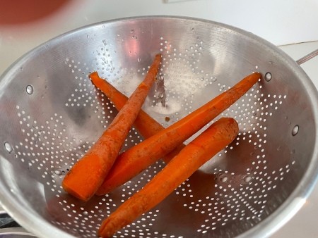 Clean carrots in a colander.