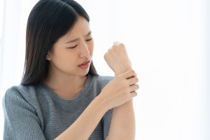 A woman holding her hand in pain.