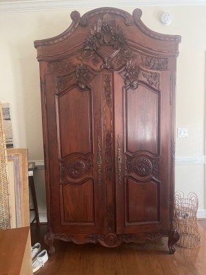 A tall wooden armoire with a carved front.