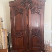 A tall wooden armoire with a carved front.