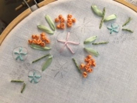 Adding small orange knots to the embroidery project.