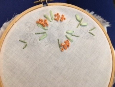 Adding small orange knots to the embroidery project.