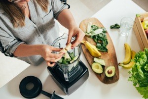 A woman making a drink in a blender.