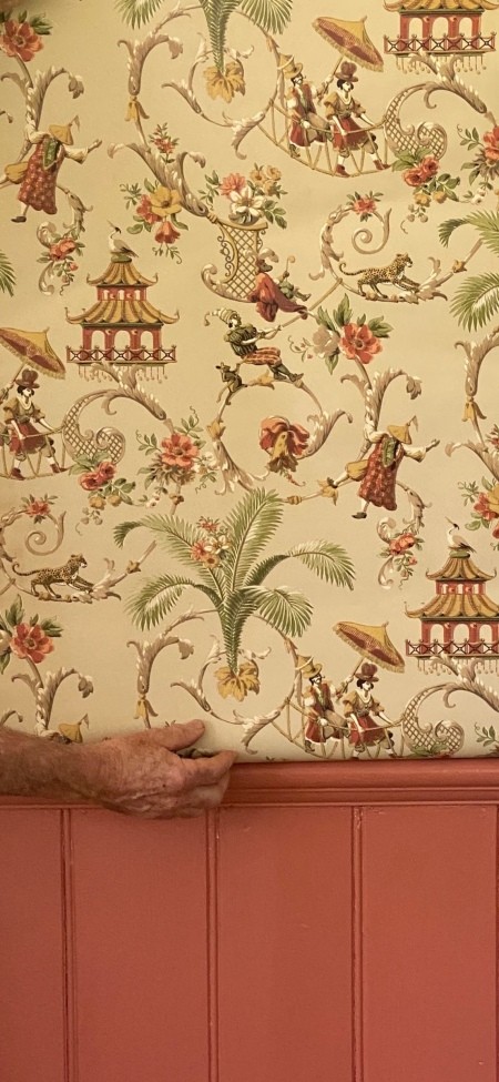 A decorative piece of wallpaper with figures, palm trees and decorative structures.