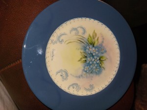 A blue china plate with a floral pattern in the center.