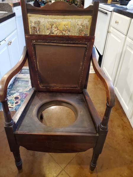 The potty seat in a wooden chair.