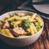 A bowl of chicken pasta with broccoli.