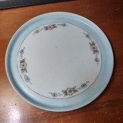 A china plate with a blue border and decorative flowers.