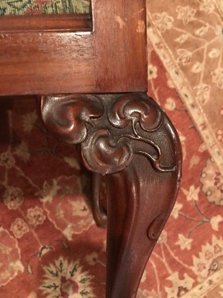 A carved foot of a wooden chair.