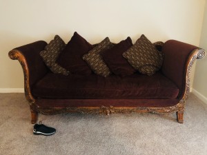 A wooden upholstered sleigh couch.