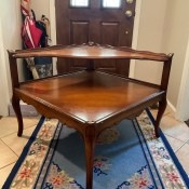 A wooden side table with a triangular shelf.