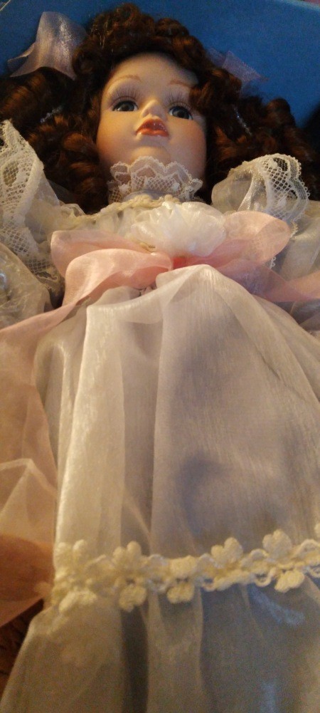 A porcelain doll wearing a white dress.