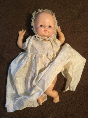 A vintage baby doll in a white gown and bonnet.