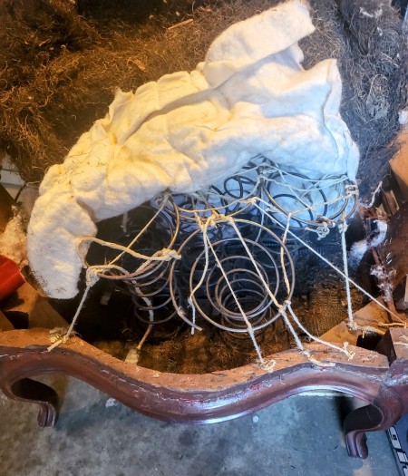 The wooden chair with springs in the seat.