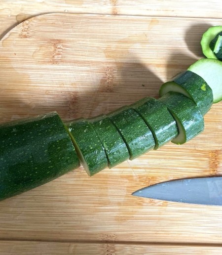 Cutting zucchini into thick round slices.