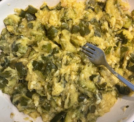 Adding cheese to the top of the zucchini mixture.