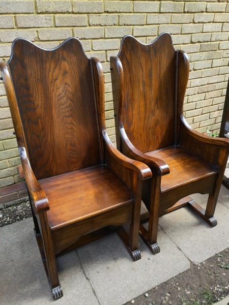 Two wooden dining chairs with arms.