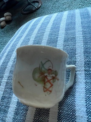 A teacup with toys on the side.