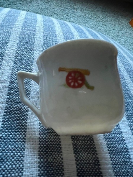 A teacup with a cannon picture on the side.
