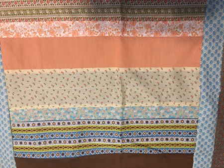 Assembling strips of fabric in a quilt pattern.