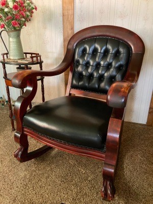 A wooden rocking chair upholstered in black leather.