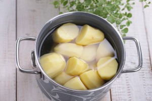 Peeled and halved potatoes in a pot of water.