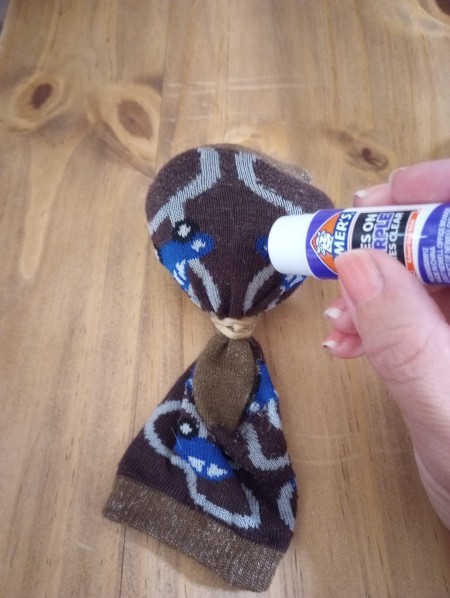 Adding glue to attach button eyes.