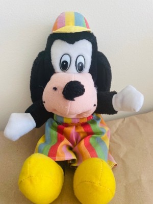 A stuffed dog wearing brightly colored clothes.