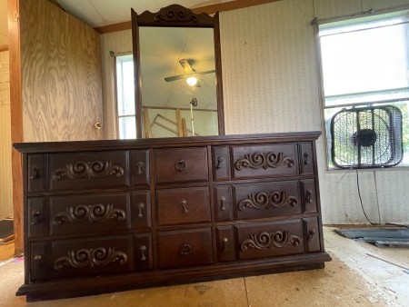 A wooden dresser with a tall mirror.
