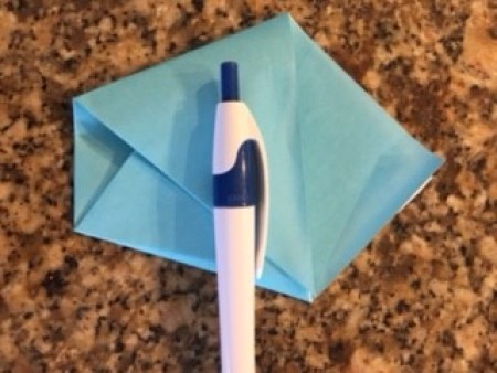 A pen holding down the folded paper.