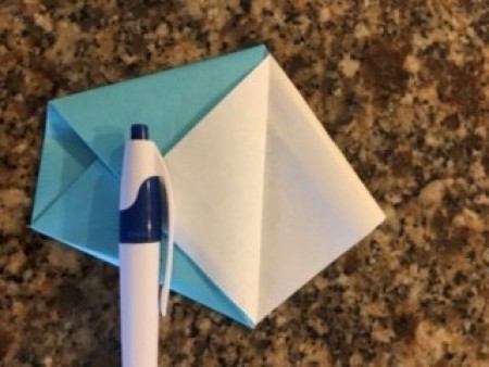 A pen holding down the fold to allow the origami to be constructed.