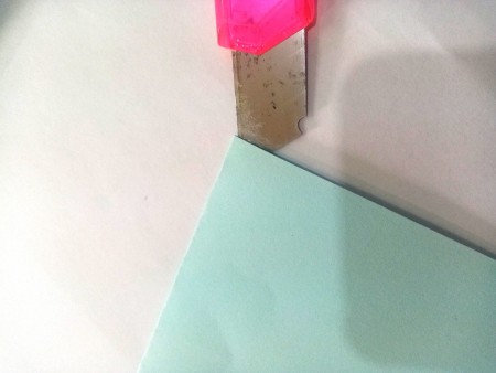 Cutting a slit at the top of the folded paper.