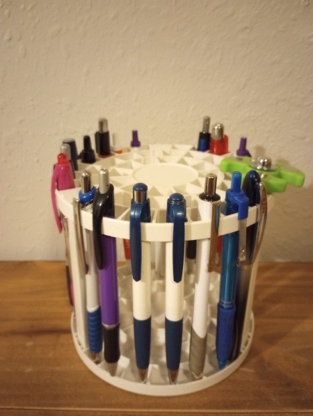 A collection of pens in a round container.