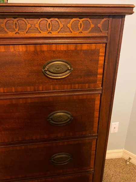 A close up of the drawers and decorative carving.
