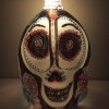 A painted milk jug to resemble a sugar skull, with a candle at the top.