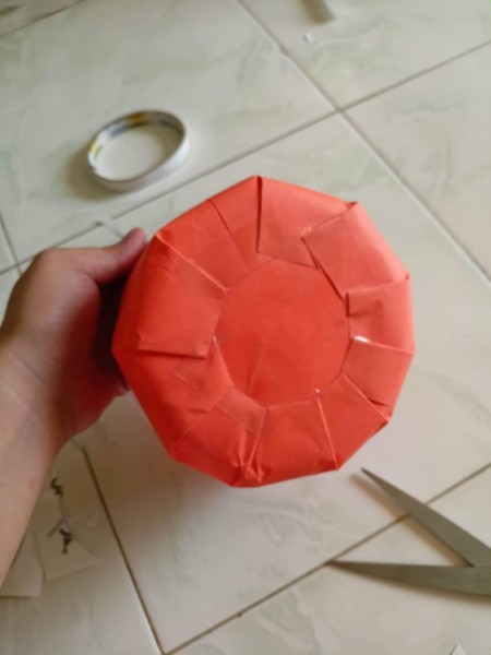 Covering plastic container with orange paper.