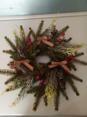 A Christmas wreath decorated with small bows and colorful berries.