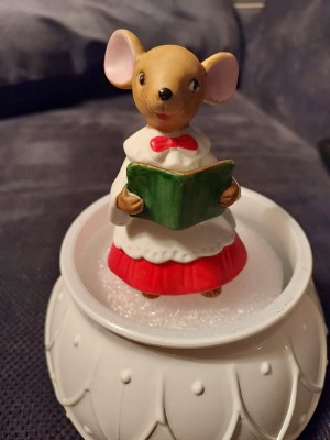 A figurine of a mouse holding a book.