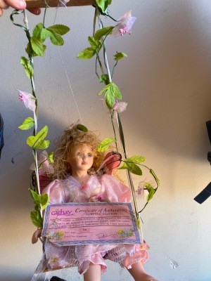 A porcelain doll on a garden swing.