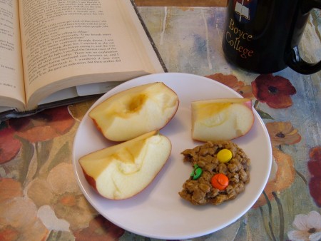 A plate with a partially eaten cookie and slices of apple.