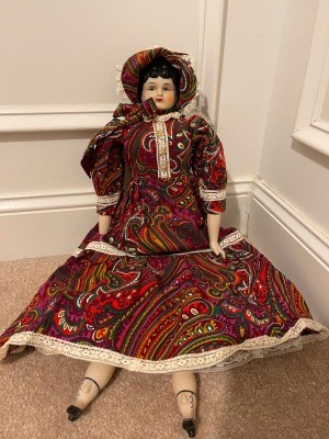A porcelain doll in an old fashioned dress.