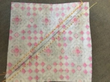 Two triangles of fabric joined as a square.