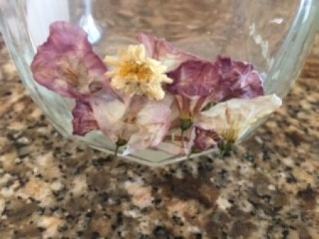 Adding dried flowers to the base of a jar.