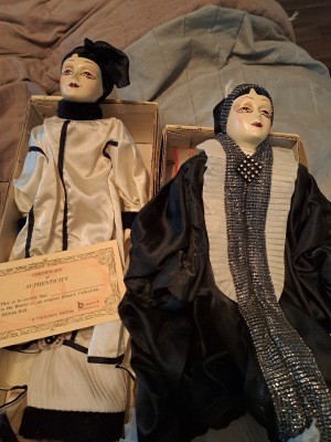 Two porcelain dolls with coats on.
