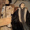 Two porcelain dolls with coats on.