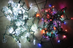 A strand of white snowflake lights next to a strand of colored lights.