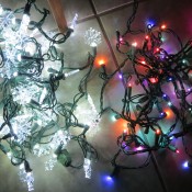 A strand of white snowflake lights next to a strand of colored lights.