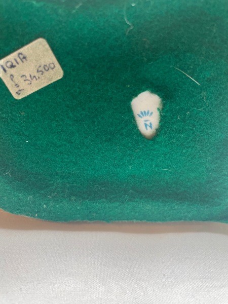 A written tag on the underside of the figurine.